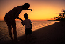 Mother And Child On The Beach Talking Looking At The Sunset. 