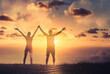 © kieferpix - Maa and woman couple together with arms up to the sunset sky. Teamwork, strength, and feeling happy and motivated concept