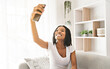 © Louis-Paul Photo - Young African American teen on a sofa in her living room using cellphone