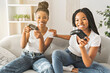 © Louis-Photo - Mother and daughter sitting on sofa at home play video game together