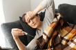© Vadim Pastuh - Senior woman checking body temperature, lying on the couch covered with a blanket, feel sick, suffering from fever