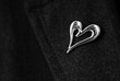wool coat lapel with elegant metal brooch in the shape of a heart, black and white image