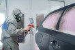 © Alvaro Atalaya/ADDICTIVE STOCK - Side view of male in respiratory mask and protective suit painting car with spray gun in service