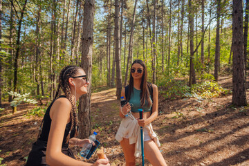 Two female caucasian friends hiking in the woods on a mountain on a nice sunny day.