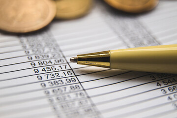 close up of a pen on a document and coins