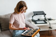woman hands playing minilogue synthesizer using mobile app at home