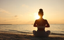 Calm Woman Meditating On Beach At Sunset