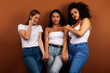 © iordani - young pretty asian, caucasian, afro woman posing cheerful together on brown background, lifestyle diverse nationality people concept