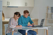 © yavdat - Man teaching his mother shopping online using laptop at home. older woman and young man using laptop together