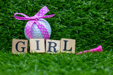 Wall Mural - Golf ball with pink ribbon for baby girl on green grass