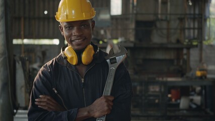 Engineer standing holding wrench tools and arms crossed at work in the industry