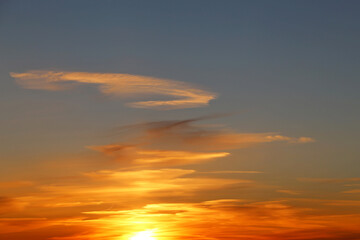 Sunset on colorful dramatic sky, white clouds in the orange sunlight. Picturesque landscape for background