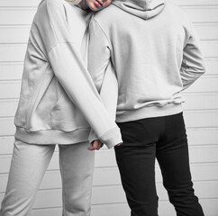 Wall Mural - Close up of hoodie on a girl. Pair of woman and man are standing in hooded jumper. Branding and design mockup template. Close up of textile fabric