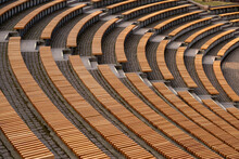 Lots Of Wooden Rounded Benches In An Empty Amphitheater Outside In The Sunshine By Day 