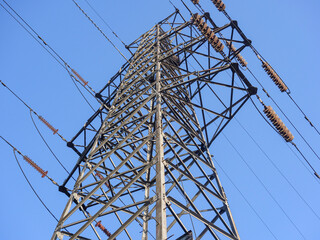 Close up of power poles and towers in the background of blue sky