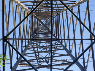 Wall Mural - Close up of power poles and towers in the background of blue sky