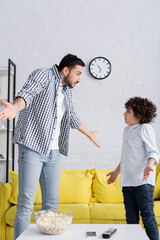 Wall Mural - confused arabian father and son showing shrug gesture while looking at each other