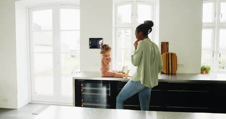 Wall Mural - Loving young African mom and her adorable little daughter eating fruit together in their kitchen at home