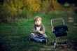 © natalialeb - Offended sad boy child sits on a path in the park in the forest with a toy baby carriage, a lonely child. Concept Children's emotions and psychology