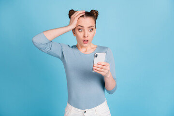 Poster - Photo of shocked surprised young woman hold hands head mistake comment smartphone isolated on blue color background