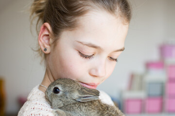 Close-up portrait of young girl with little brown bunny. Symbol of animal care, beauty, love and easter.