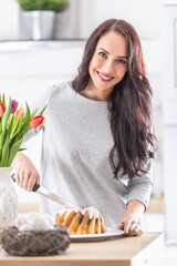 Young woman cutting sweet easter cake during holidays