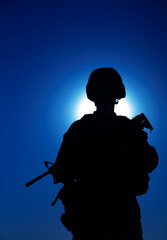 Silhouette of army infantry soldier armed assault rifle on background of night sky with moon. Special operations forces fighter in combat helmet and uniform during night mission, military sentry duty