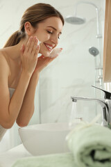 Canvas Print - Young woman applying cleansing foam onto her face in bathroom