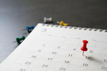 close up of pin on calendar on the black table background, planning for business meeting or travel planning concept