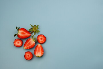 Wall Mural - Halves of ripe juicy strawberries on a blue background.