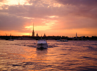 Saint-Petersburg, Russia, 03 September 2020: A tourist boat sails along the Neva River at sunset, with the Peter and Paul Fortress in the background.