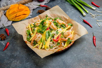 Wall Mural - Vietnamese shrimp salad with greens amd mango on beautiful dark stone table