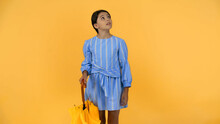 preteen girl in blue dress standing with umbrella on yellow