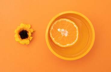 Wall Mural - Flower, bowl and fruit on orange background. Monochrome arrangement orange color.