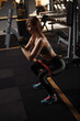 © Ihor - Vertical shot of a female athlete exercising with resistance band at the gym, doing squats