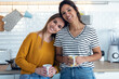 © nenetus - Two beautiful woman friends having breakfast and drinking coffee while talking in the kitchen at home.