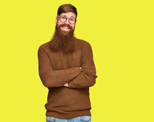 Wall Mural - Young irish redhead man wearing casual clothes and glasses happy face smiling with crossed arms looking at the camera. positive person.