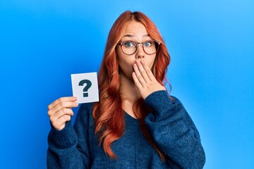 Poster - Young beautiful redhead woman holding question mark covering mouth with hand, shocked and afraid for mistake. surprised expression