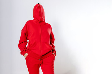 front view of a girl in a red tracksuit with a hood buttoned on her head on a white background, copy space