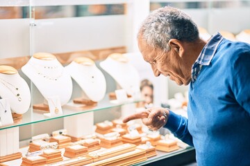 Wall Mural - senior grey-haired man smiling happy looking to showcase jewelry shop.