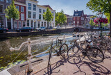 Fototapeta Zachód słońca - Bunch of bicycles standing by canal in Leiden, the Netherlands