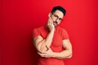 © Krakenimages.com - Young hispanic man wearing casual clothes and glasses thinking looking tired and bored with depression problems with crossed arms.