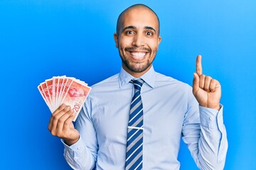 Sticker - Hispanic adult man holding 20 israel shekels banknotes smiling with an idea or question pointing finger with happy face, number one