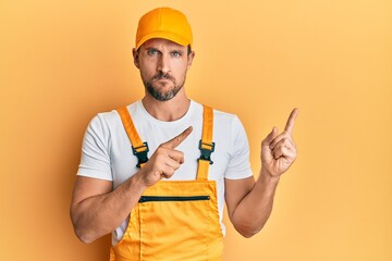 Poster - Young handsome man wearing handyman uniform pointing to the side skeptic and nervous, frowning upset because of problem. negative person.