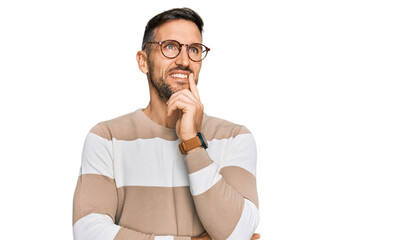 Wall Mural - Handsome man with beard wearing casual clothes and glasses with hand on chin thinking about question, pensive expression. smiling and thoughtful face. doubt concept.