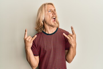 Sticker - Caucasian young man with long hair doing rock gesture angry and mad screaming frustrated and furious, shouting with anger. rage and aggressive concept.