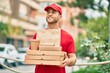 © Krakenimages.com - Young caucasian deliveryman smiling happy holding delivery food at the city.