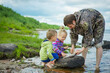 a fisherman with children and a pike on the river bank, selective focus