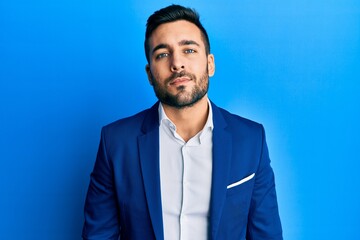 Young hispanic businessman wearing business jacket relaxed with serious expression on face. simple and natural looking at the camera.