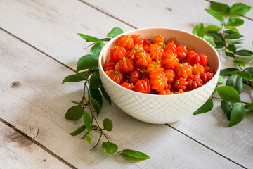 Surinam cherry in a white bowl on a wooden table.